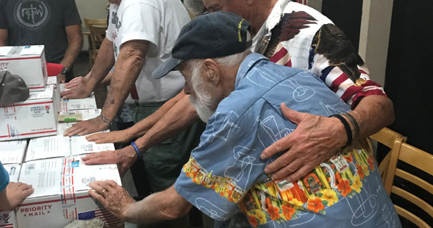 A group of people are praying for care packages and laying hands on them