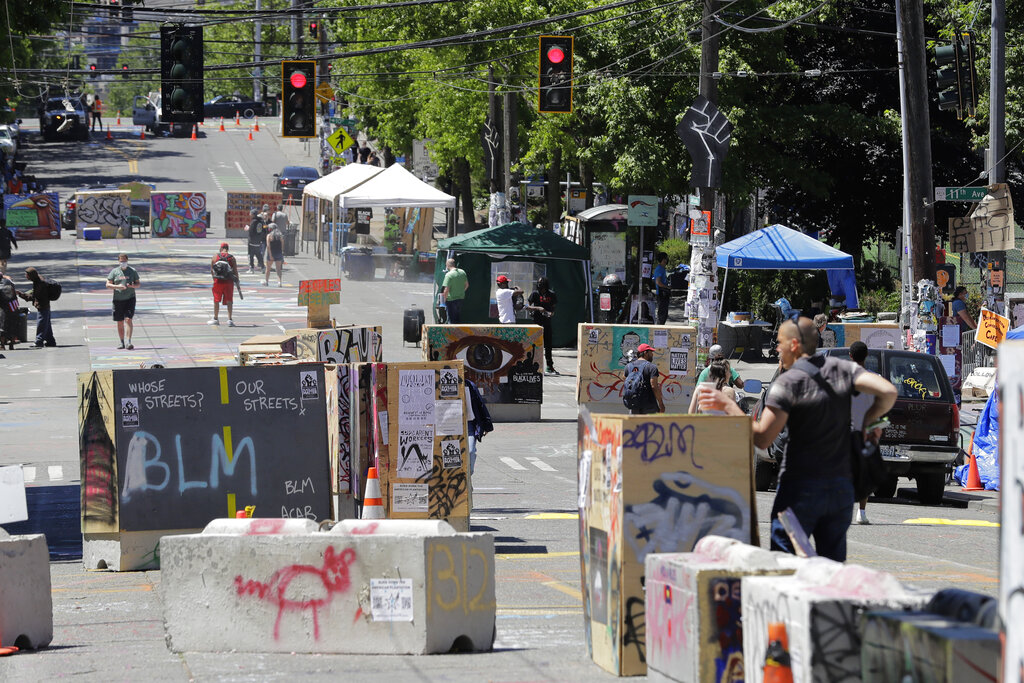 People walk amidst barricades in what has been named the Capitol Hill Occupied Protest zone in Seattle