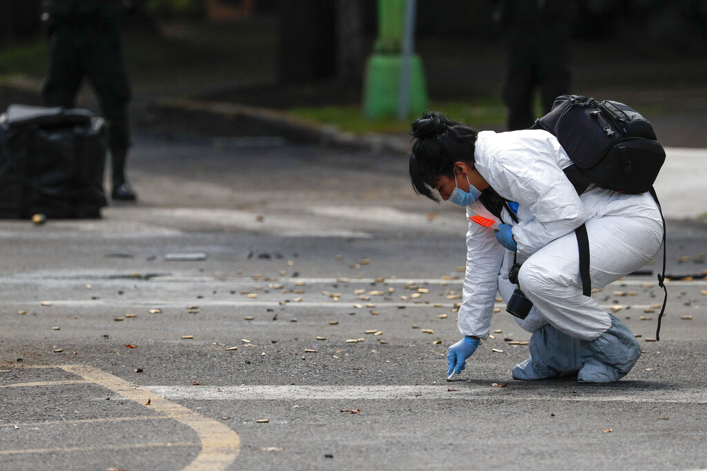 A forensic investigator collects cartridges at the scene