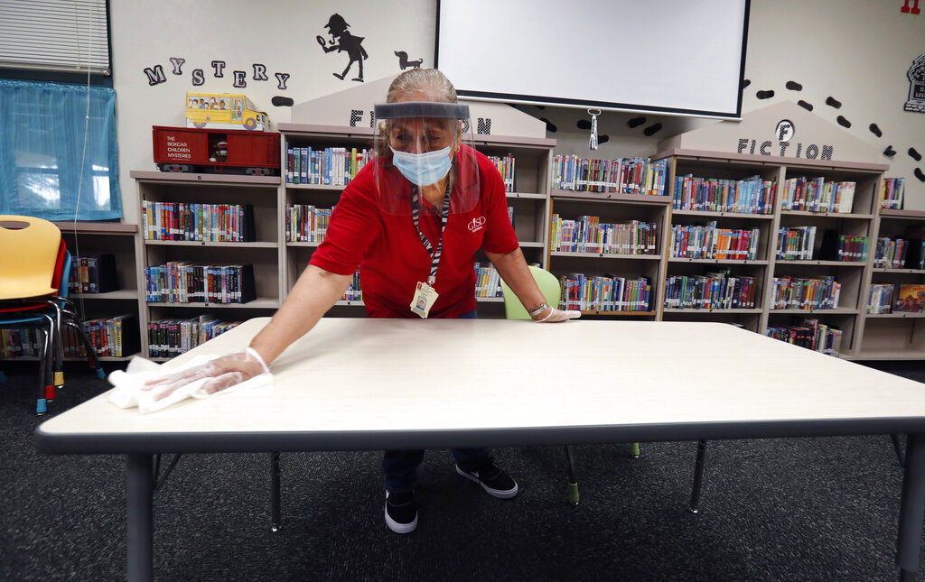 Garland Independent School District custodian Camelia Tobon wipes down a table in the library at Stephens Elementary School in Rowlett, Texas