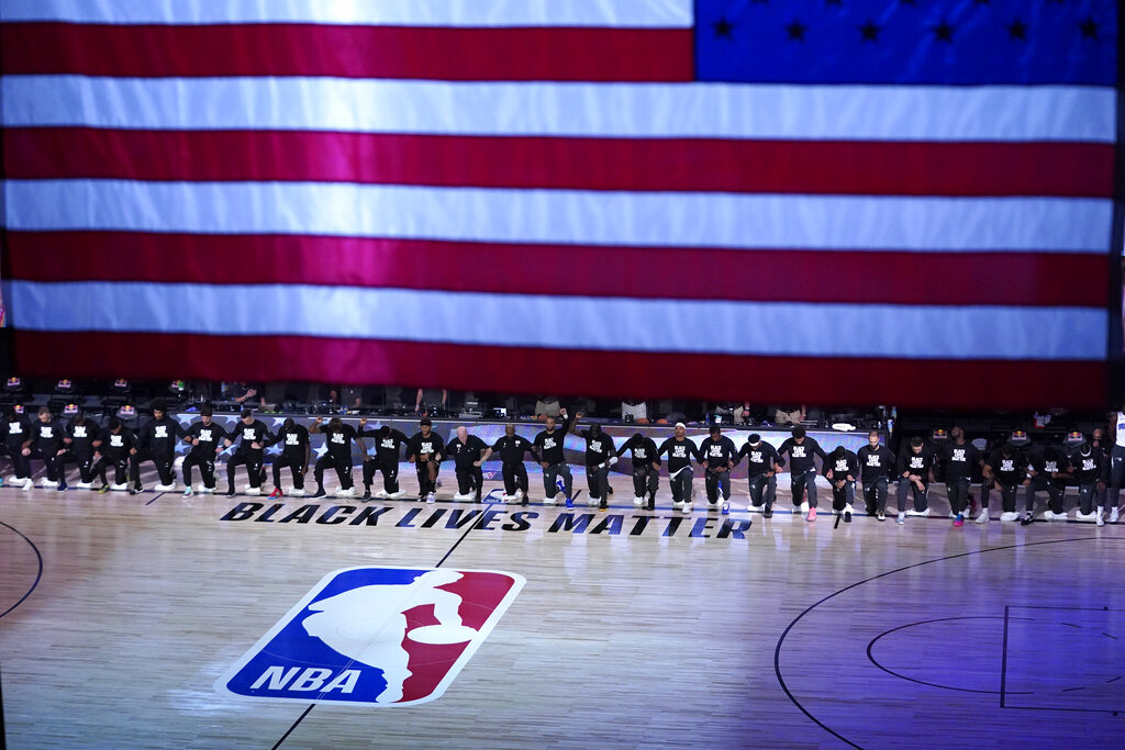 Members of the Orlando Magic and Brooklyn Nets kneel around a Black Lives Matter logo