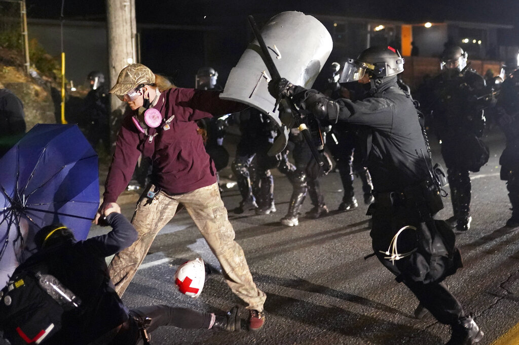 Portland police officer shoves a protester as police try to disperse the crowd in front of the Multnomah County Sheriff
