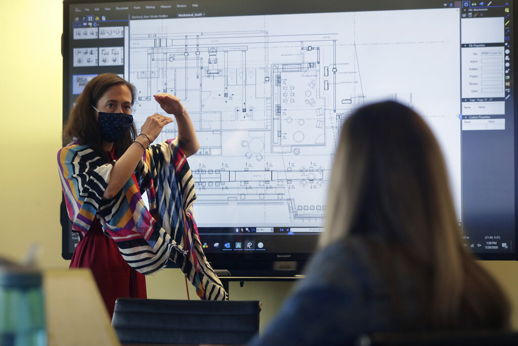 Interior designers Stephanie Jones, left, and Tara Martin, right, work in a conference room at the design firm Bergmeyer