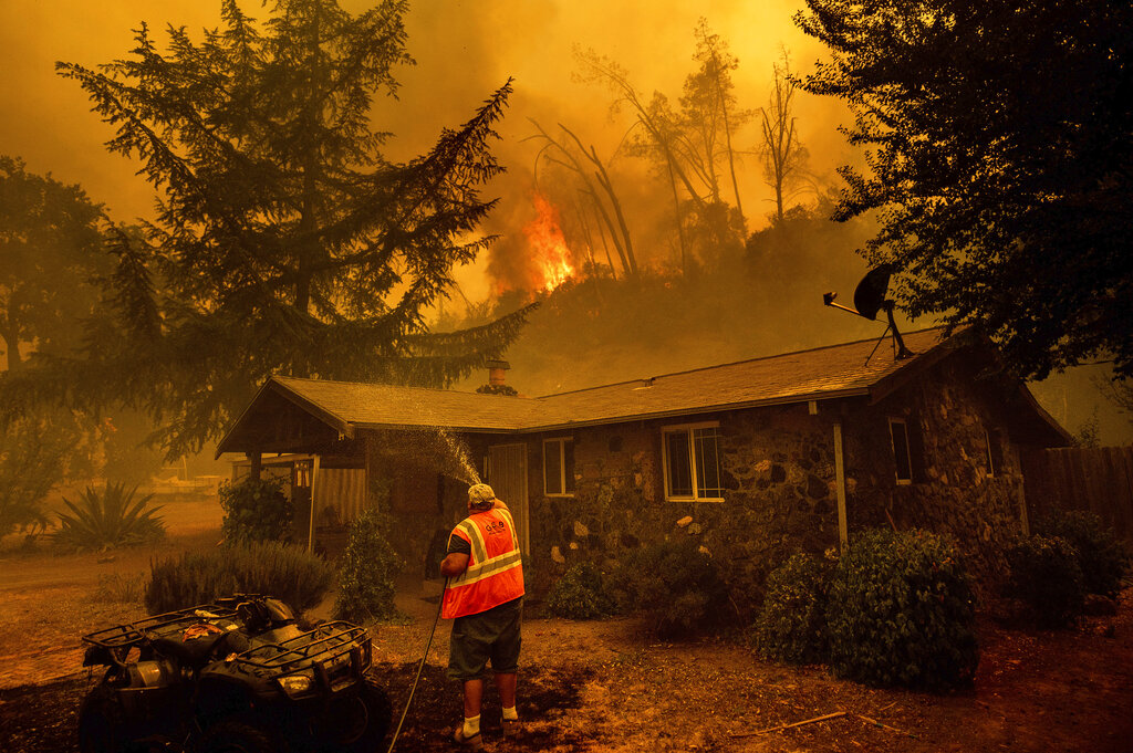  Jerry Kuny sprays water on a home as flames from the LNU Lightning Complex fires approach in unincorporated Napa County, Calif. This home remained standing as the main front passed although the fire went on to destroy multiple residences. 