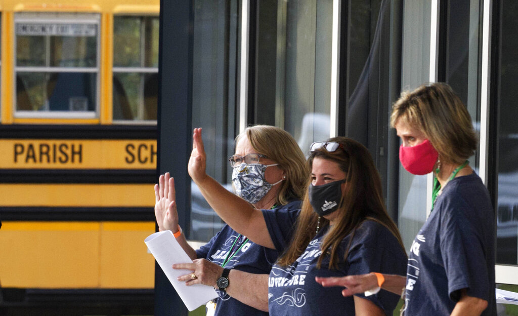 Educators welcome students on the first day of class at Lake Harbor Middle School with coronavirus restrictions in Mandeville, La.