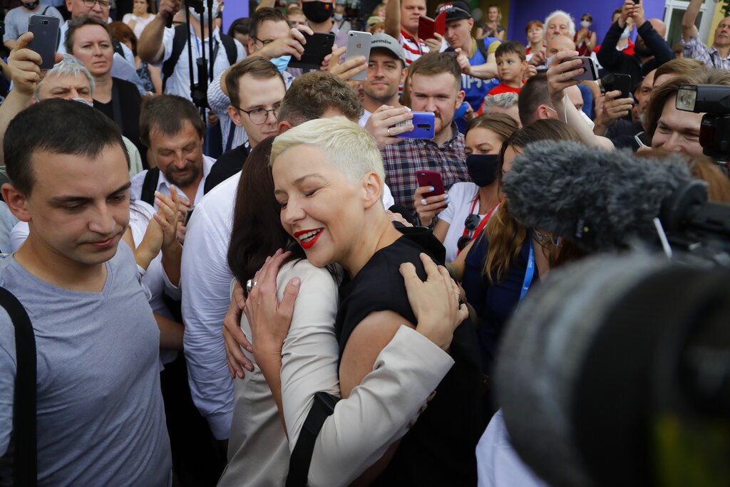 Sviatlana Tsikhanouskaya, candidate for the presidential elections, center left, and Maria Kolesnikova, a representative of Viktor Babariko, center right, greet each other at a polling station