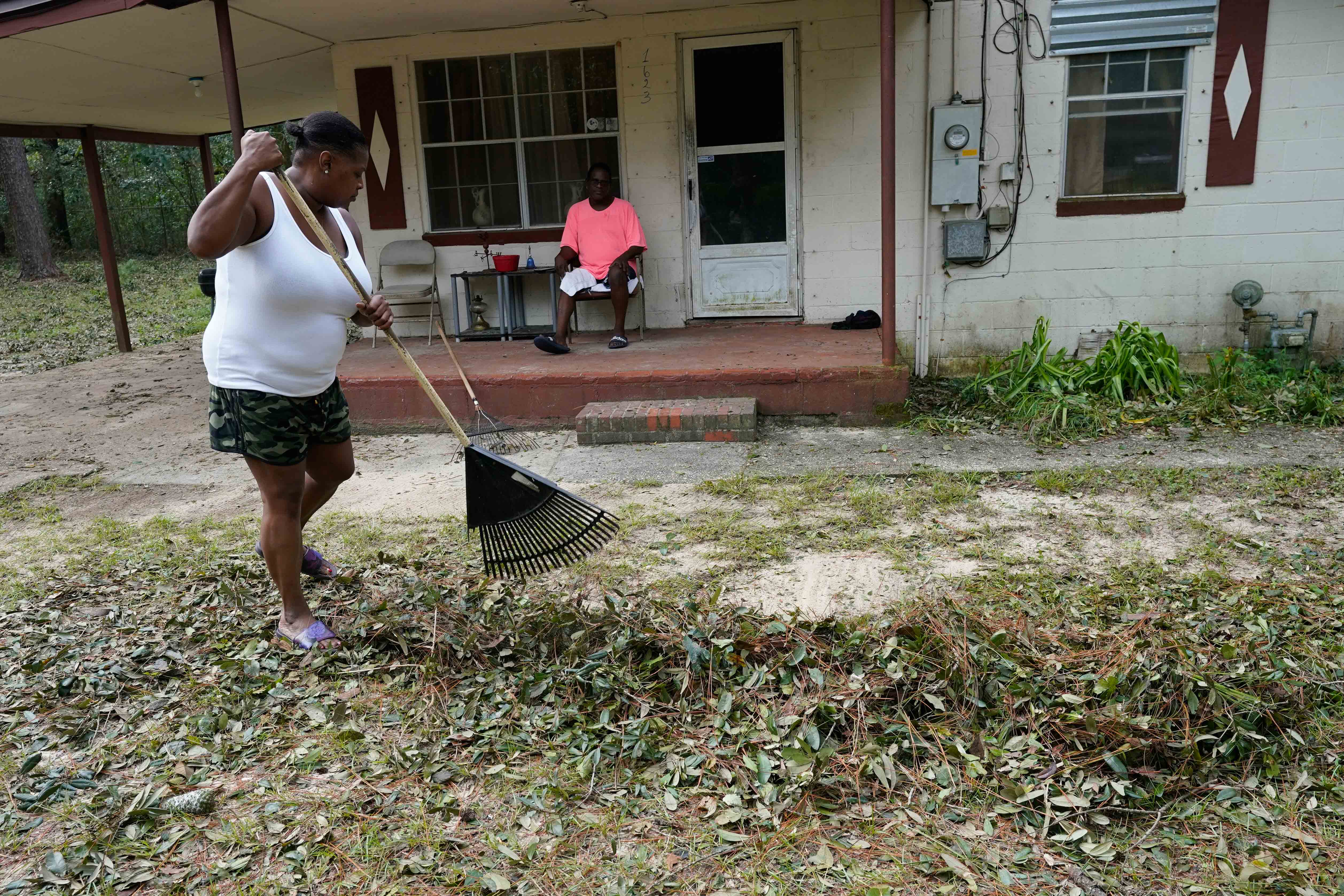 Woman cleans up debris from Hurricane Sally in front of house