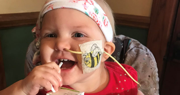Baby with catheter in nose drinking a juice box