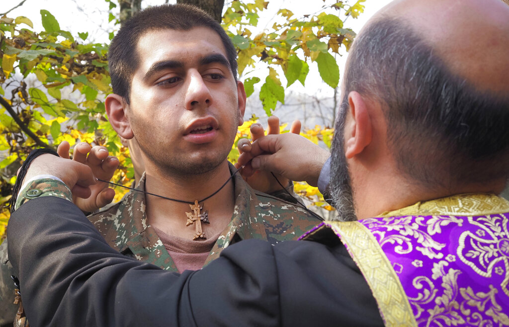 Priest Aristakes Hovhannisyan places a crucifix on an ethnic Armenian soldier 