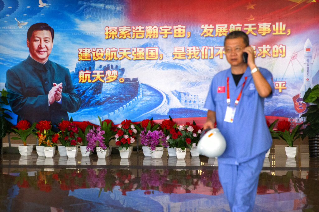 A worker walks past a billboard with a quotation from Chinese President Xi Jinping in a building at the Wenchang Space Launch Site 