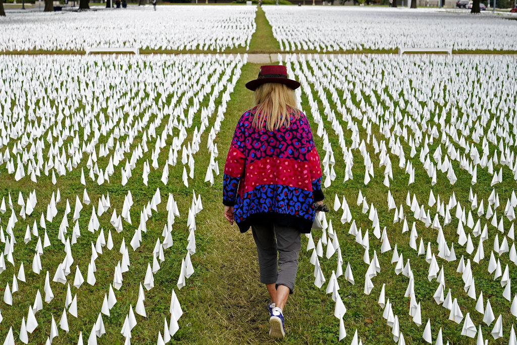 Artist Suzanne Brennan Firstenberg walks among thousands of white flags planted in remembrance of Americans who have died of COVID-19 near Robert F. Kennedy Memorial Stadium in Washington.
