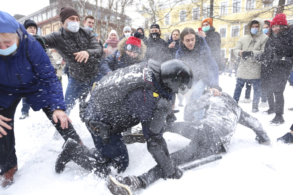 Policeman detains a man while protesters try to help him, during a protest against the jailing of opposition leader Alexei Navalny in St. Petersburg, Russia