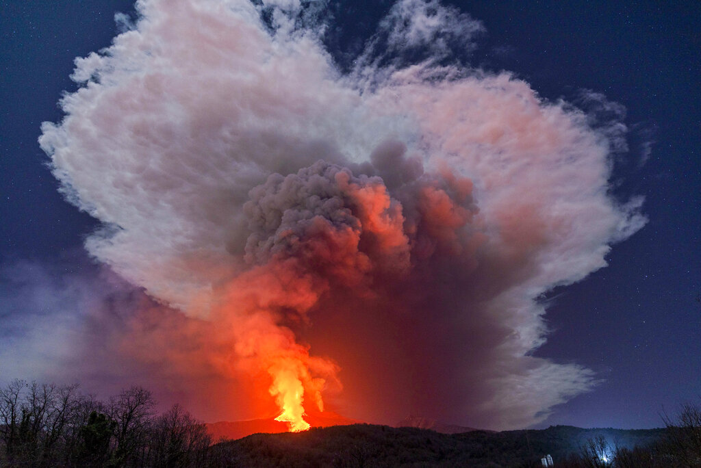 A fiery river of glowing lava flows on the north-east side of the Mt Etna volcano engulfed with ashes and smoke near Milo, Sicily