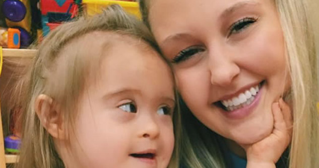 Toddler with down syndrome touches face of smiling woman