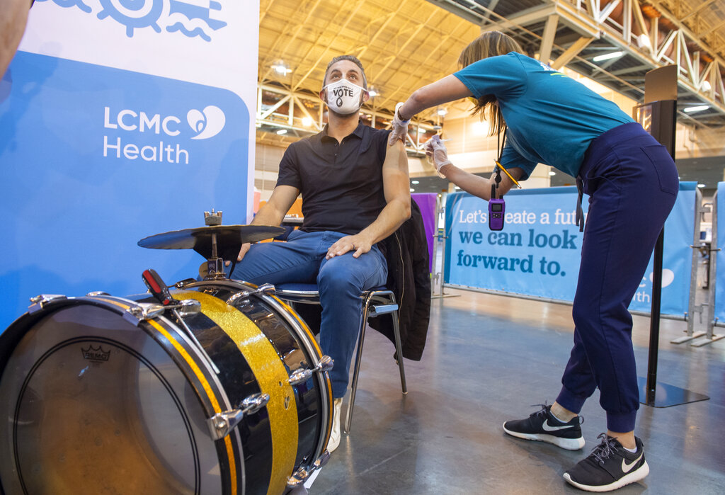 Drummer Kyle Sharamitaro looks away as Registered Nurse Allison Guste administers the Johnson & Johnson COVID-19 vaccine at the New Orleans Ernest N. Morial Convention Center