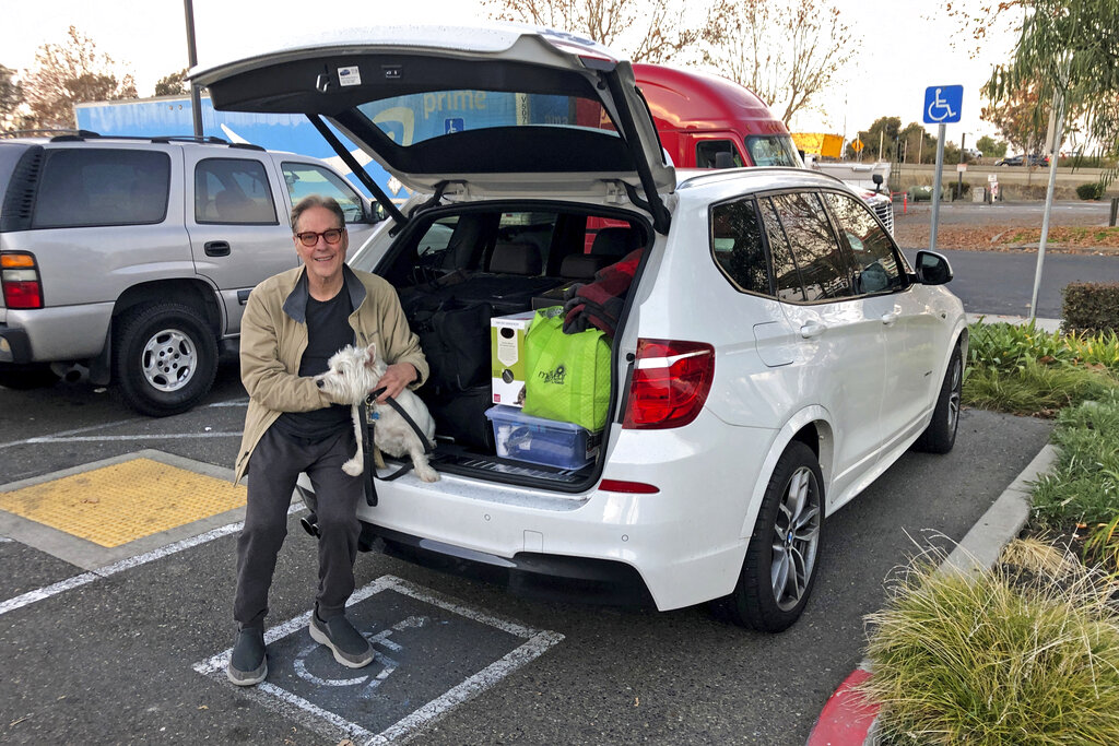 Matt Frinzi poses with his dog and his belongings, in West Sacramento, Calif. Prinzi who has lived in California for 25 years officially moved to Reno, Nevada.