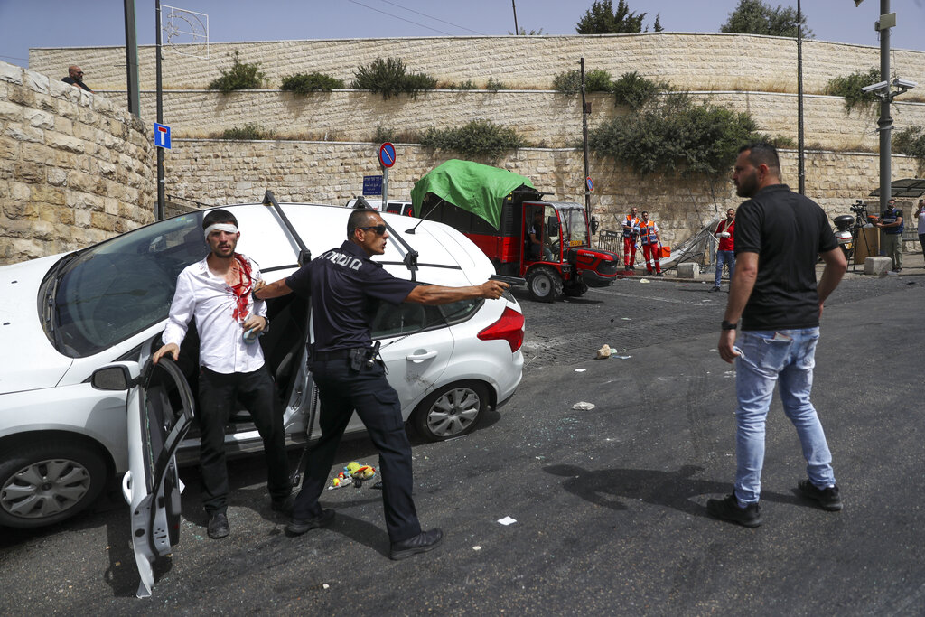 Israeli police officer protects a Jewish driver who was attacked by Palestinian protesters near Jerusalem