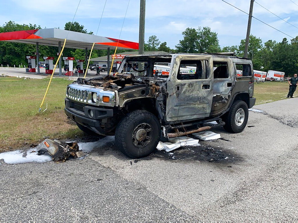 Citrus County Fire Rescue an officer stands near a Hummer which was destroyed by fire shortly after the driver had filled up four 5-gallon (18-liter) gas containers in Homosassa, Fla. 