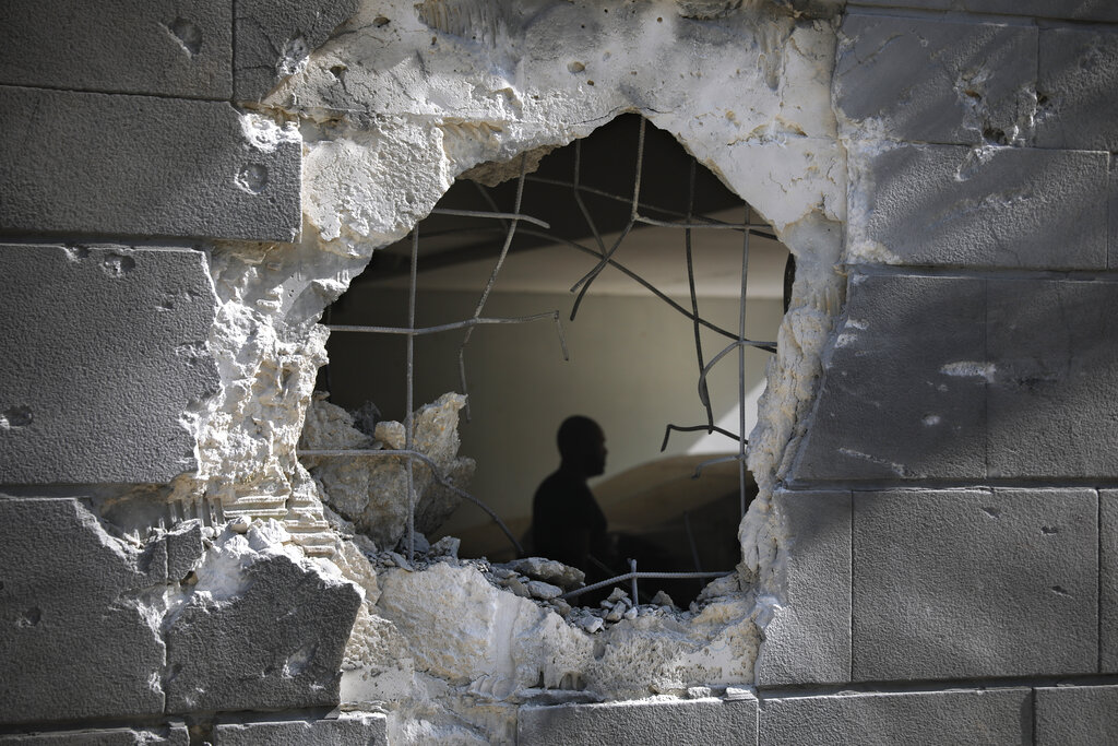 A man is seen trough a hole in a wall of a residential building after it was struck by a rocket fired from the Gaza Strip in Ashkelon, Israel