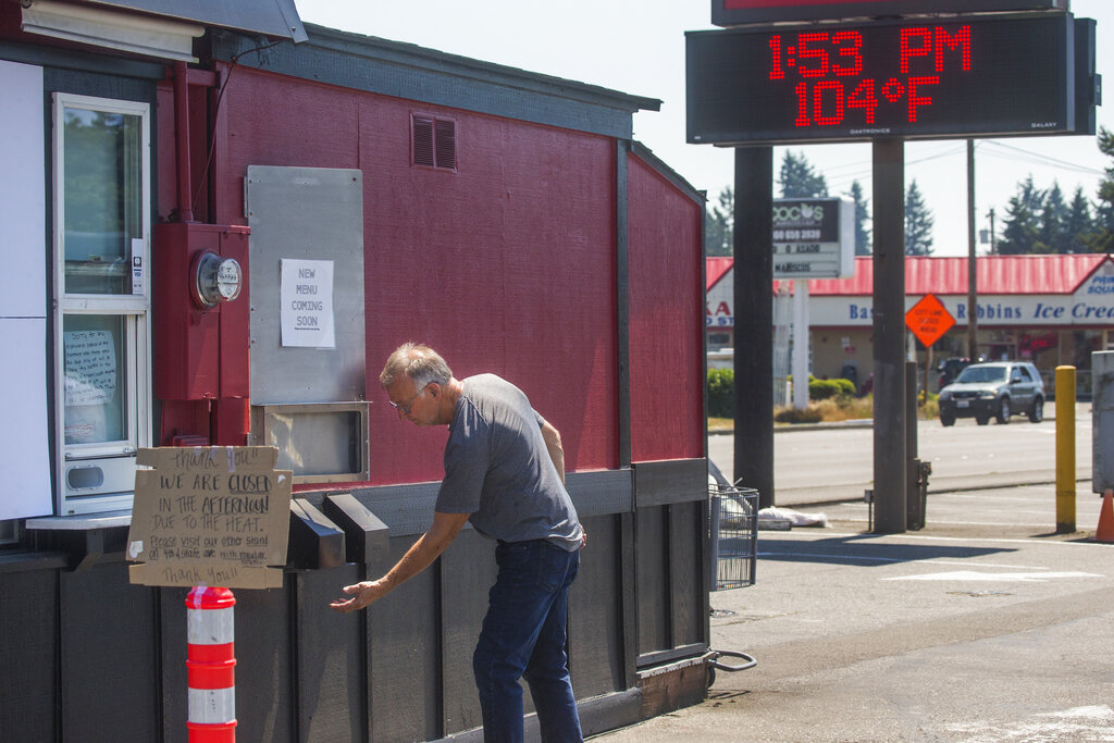 Jim Martin, owner of Espresso Connection, feels the heat from a vent at one of his Marysville coffee stands, closed for the afternoon due to excessive heat