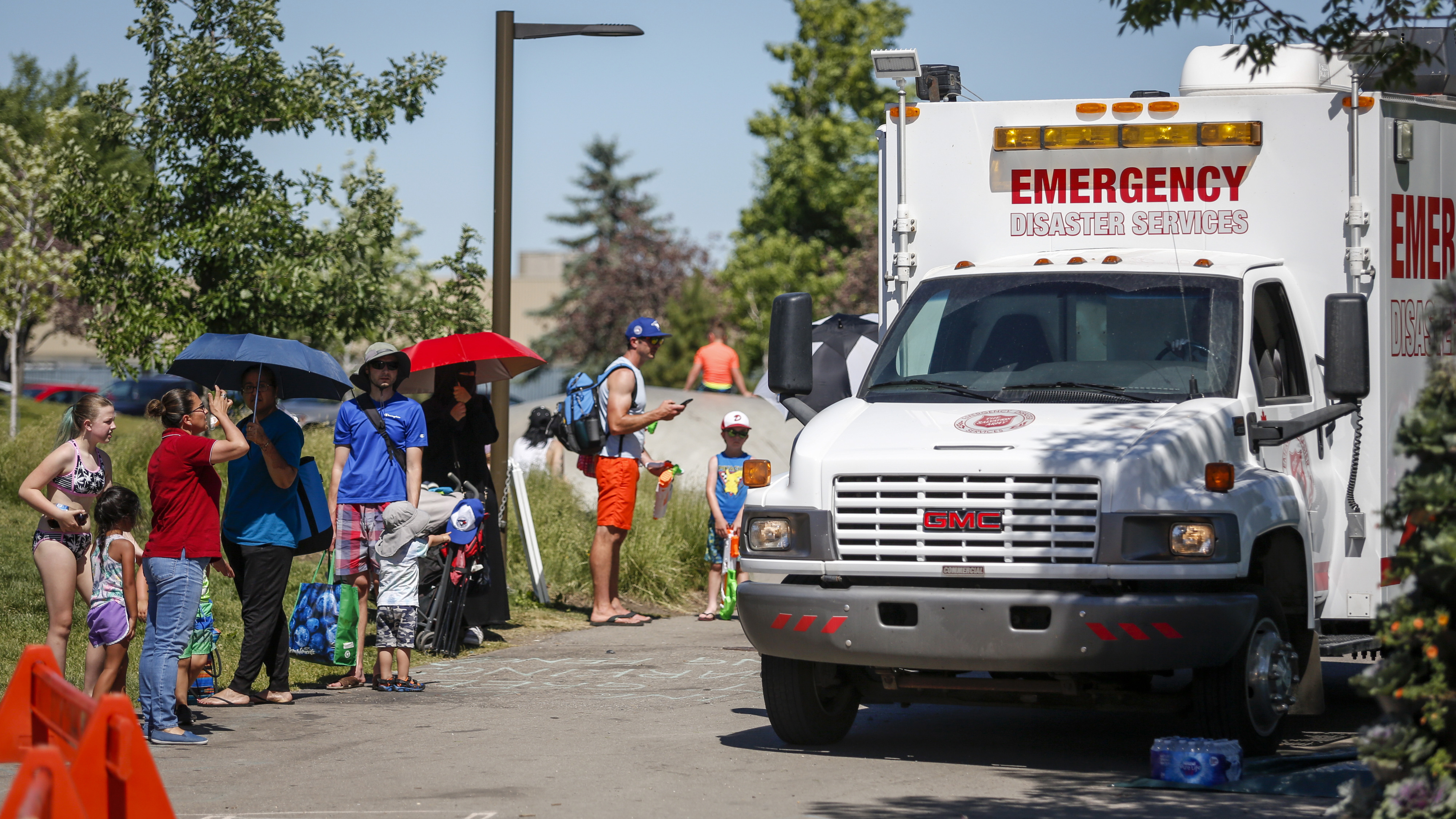 A Salvation Army EMS vehicle is setup as a cooling station as people lineup to get into a splash park while trying to beat the heat in Calgary, Alberta.