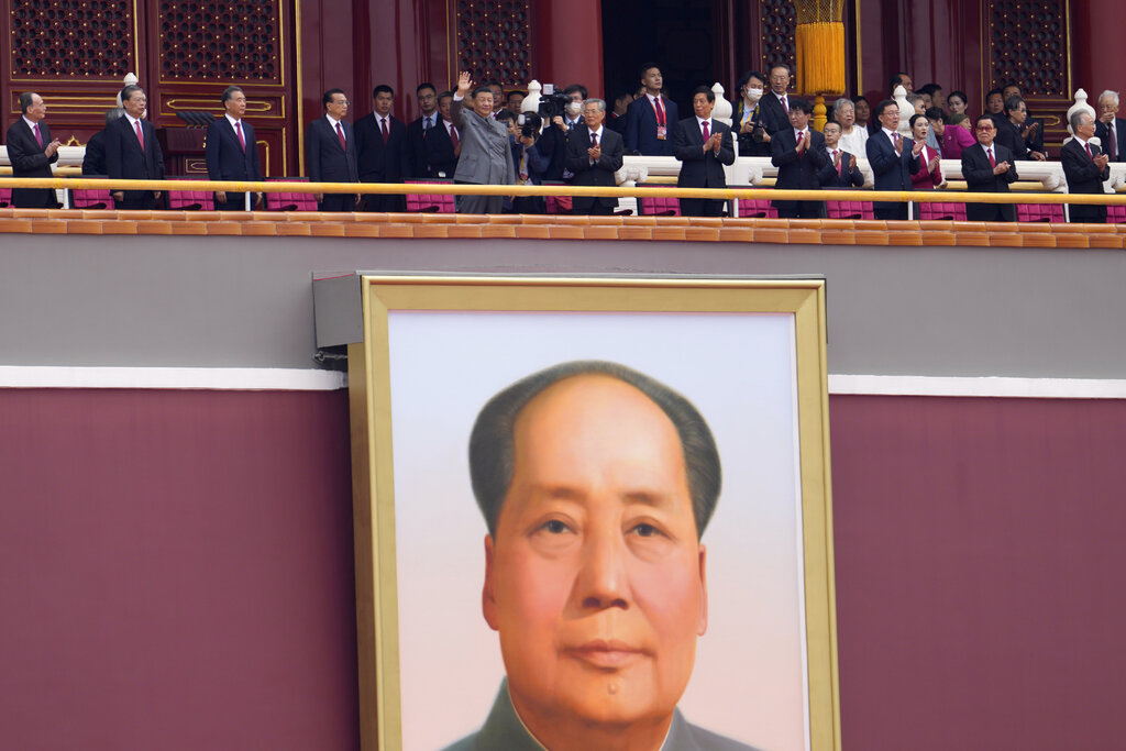 Chinese President Xi Jinping, center, waves above a large portrait of the late leader Mao Zedong