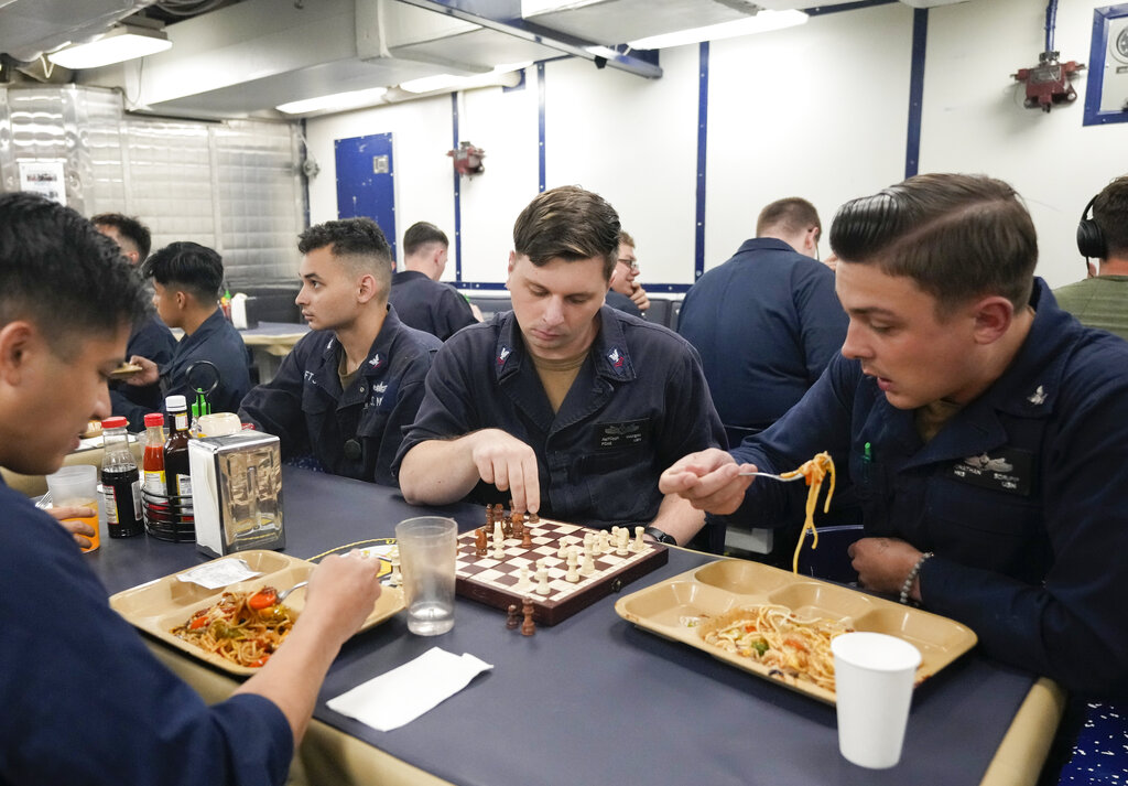 Sailors of the guided-missile destroyer USS Ross, eat and play chess as they rest during Sea Breeze 2021 maneuvers, in the Black Sea