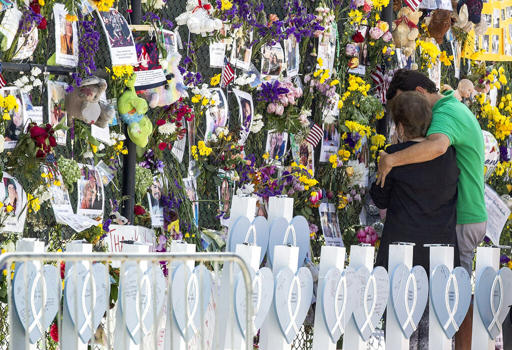 People mourn at the memorial wall for the victims of the Champlain Towers South collapse, in Surfside, Fla. 