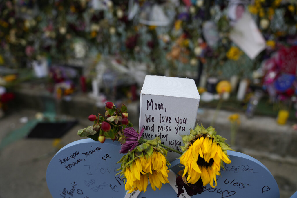 Flowers and messages of love adorn a wooden heart marked with the name Francis Fernandez, alongside a memorial wall for the victims of the Champlain Towers South building collapse