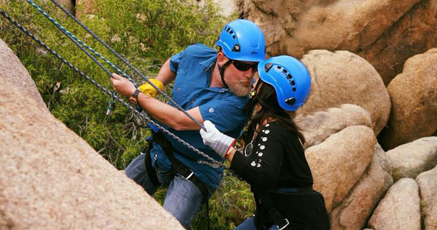 Husband and wife kiss while rock climbing