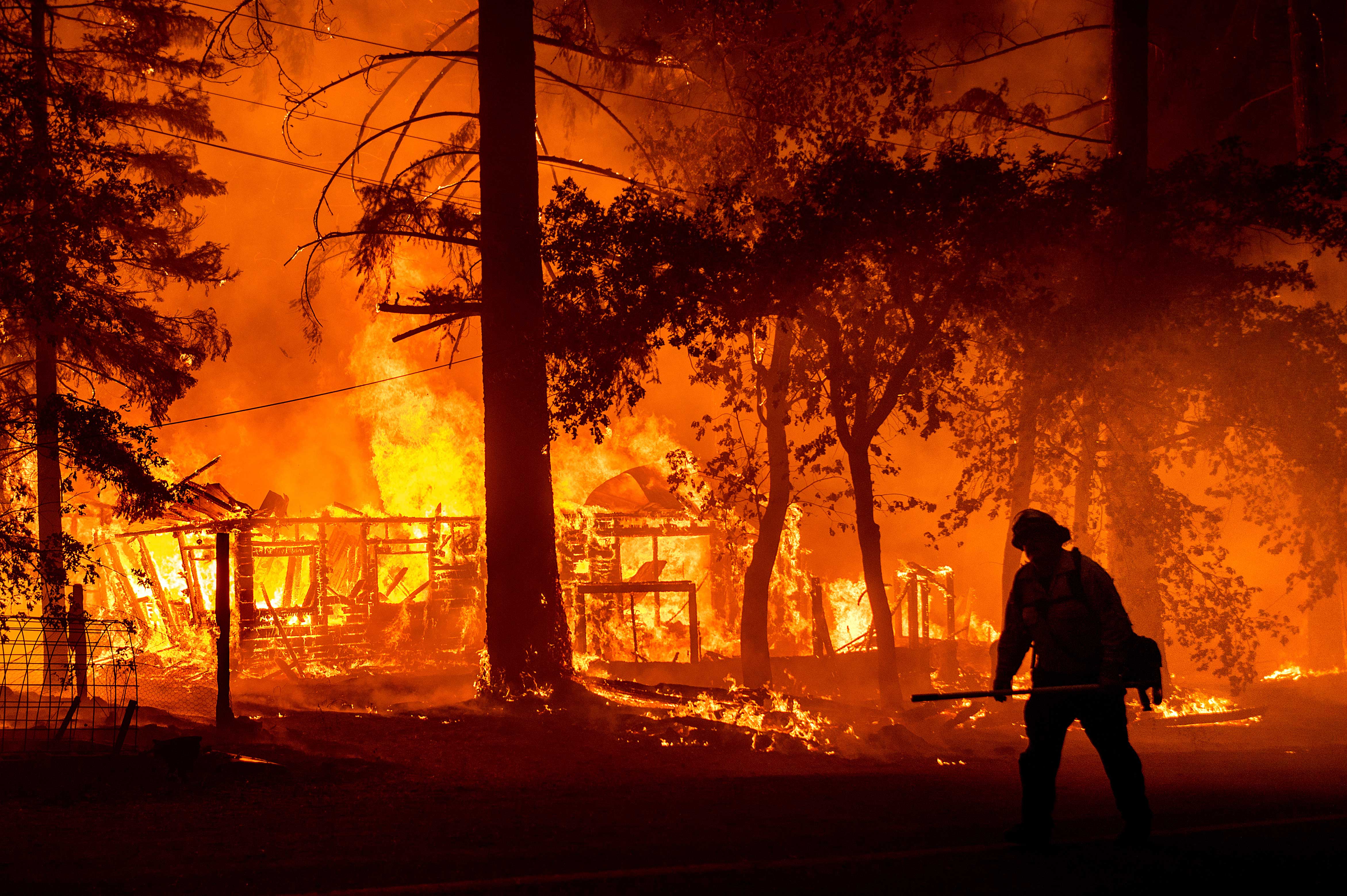 A firefighter passes a burning home