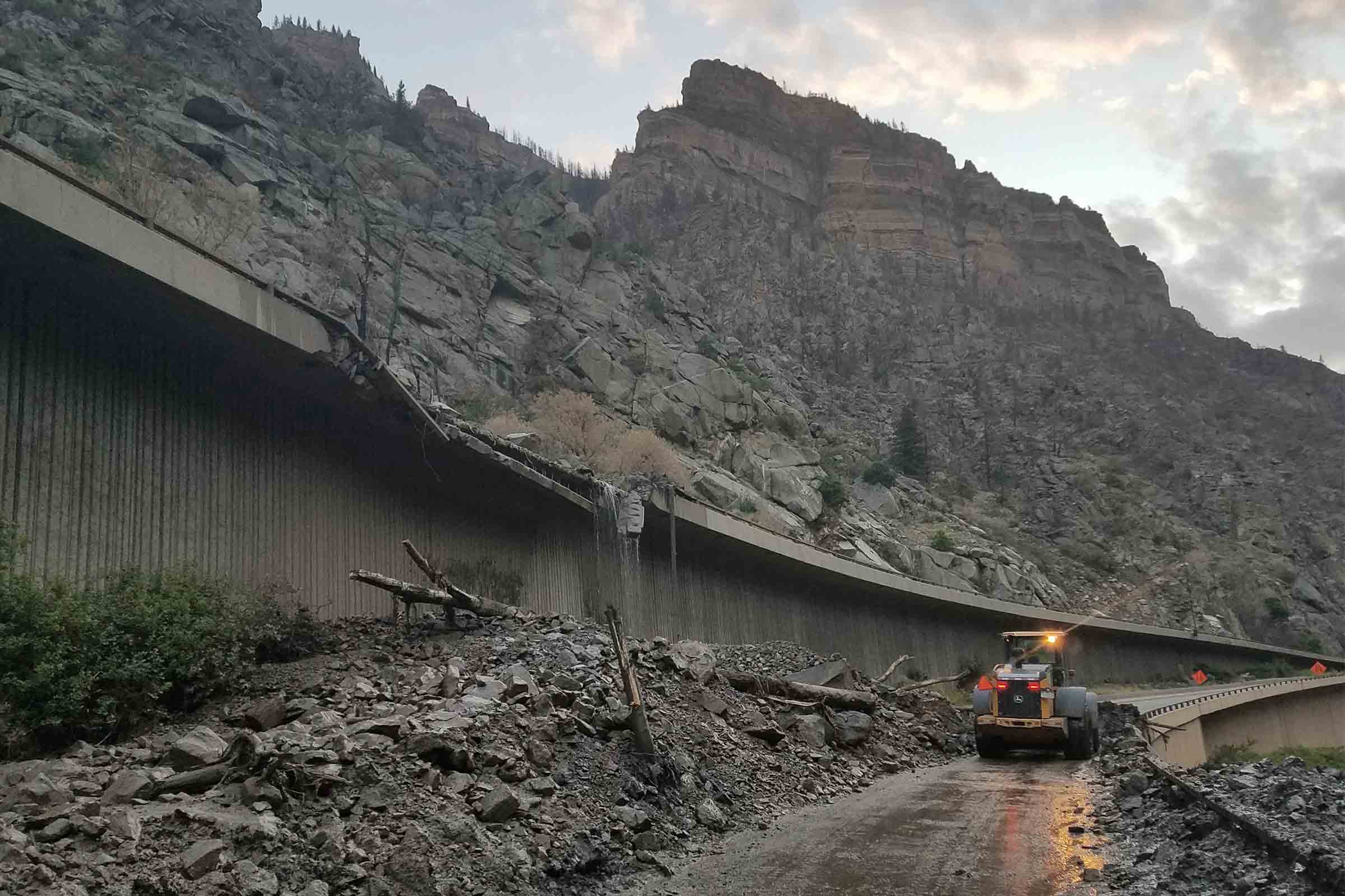 In this photo provided by the Colorado Department of Transportation, equipment works to clear mud and debris from a mudslide on Interstate-70 through Glenwood Canyon, Colo.