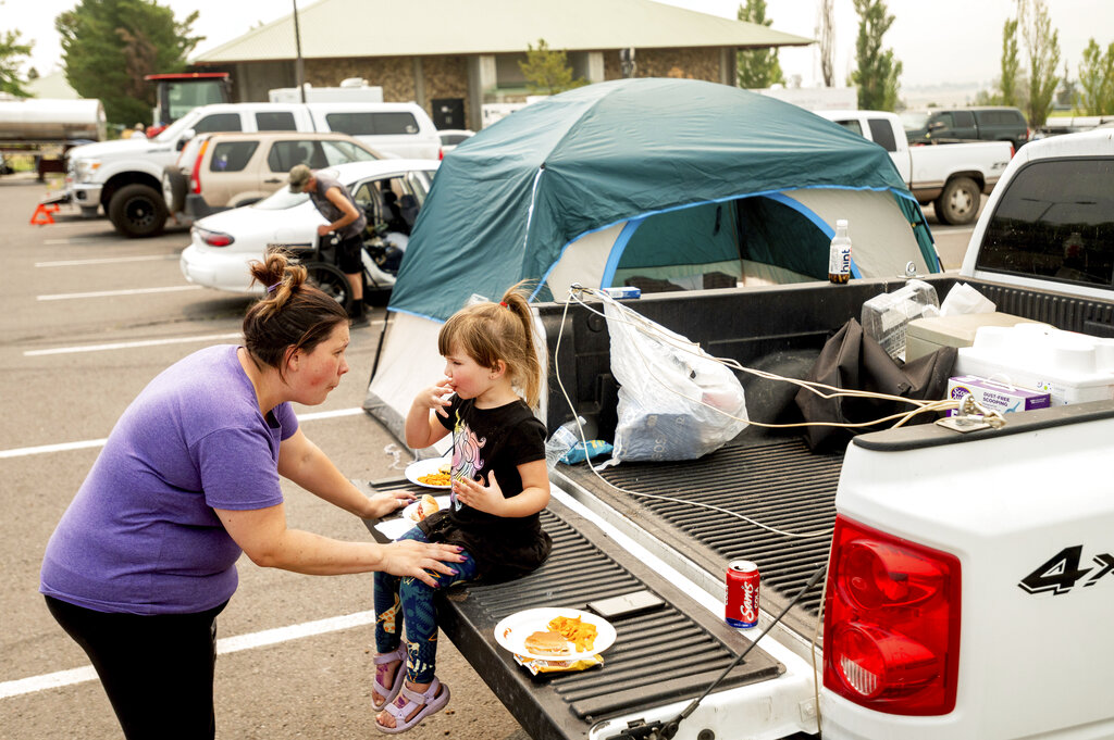 Jackie Armstrong, a Chester resident evacuated from the Dixie Fire, speaks with daughter Zoey Armstrong, 3, at a Susanville, Calif., evacuation shelter