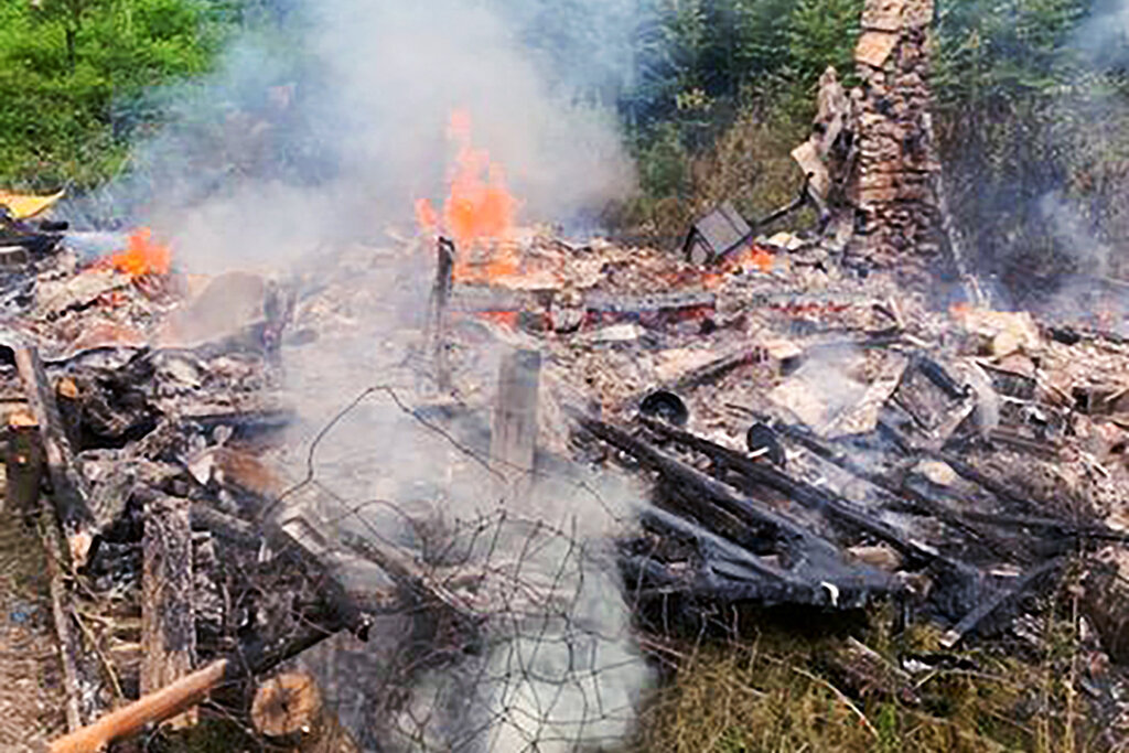 Smoke rises from the burnt remains of a cabin in Canterbury, N.H., inhabited by 81-year-old David Lidstone, who for 27 years has lived in the woods