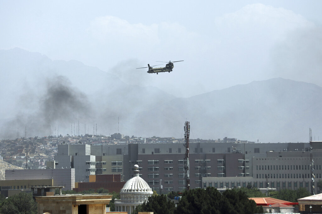 U.S. Chinook helicopter flies near the U.S. Embassy, left, in Kabul. Helicopters are landing at the U.S. Embassy in Kabul as diplomatic vehicles leave the compound.