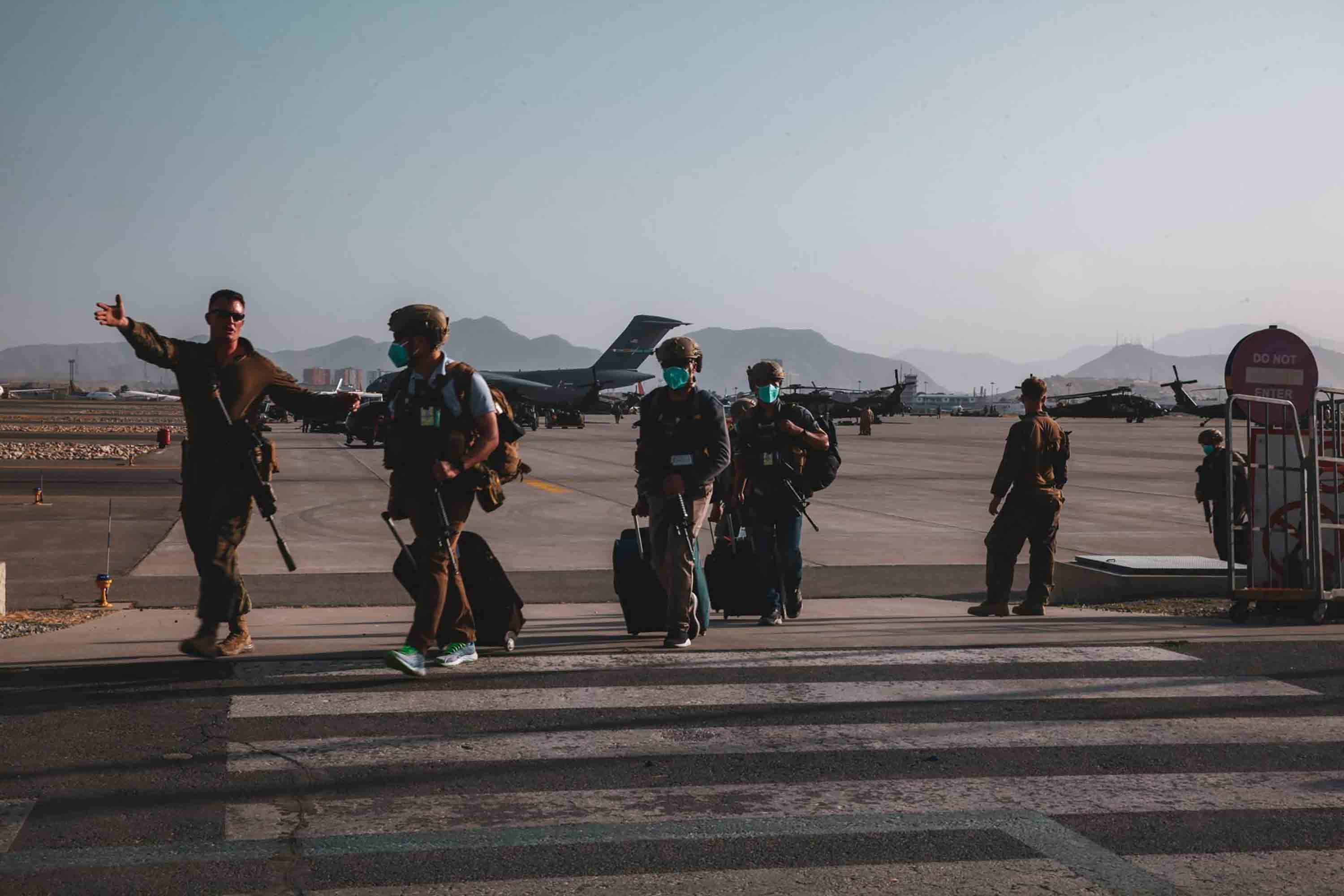 A Marine assigned to the 24th Marine Expeditionary Unit (MEU) escorts Department of State personnel to be processed for evacuation at Hamid Karzai International Airport, in Kabul, Afghanistan, Sunday, Aug. 15, 2021.