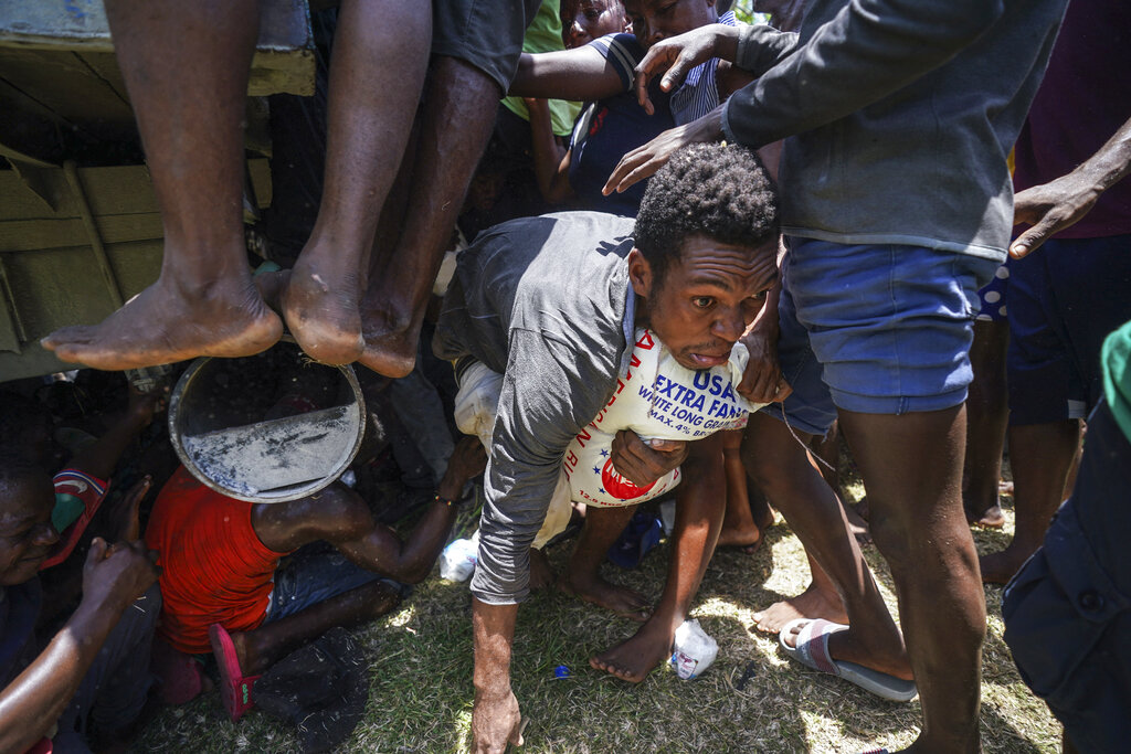 A resident crawls away with a donated bag of rice after residents temporarily overtook a truck loaded with relief supplies