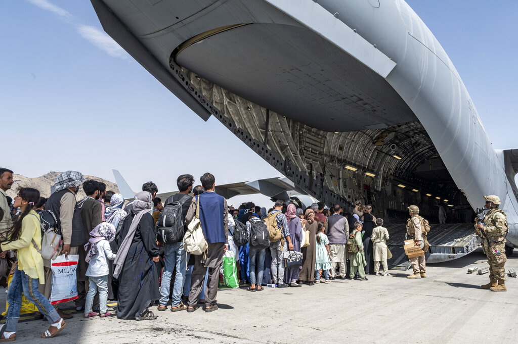 U.S. Airmen and U.S. Marines guide evacuees aboard a U.S. Air Force C-17 Globemaster III in support of the Afghanistan evacuation at Hamid Karzai International Airport in Kabul