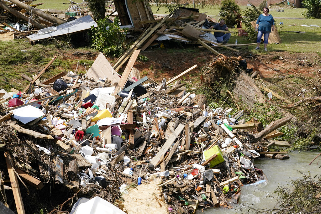 A woman looks at debris that came to rest against a bridge over a stream
