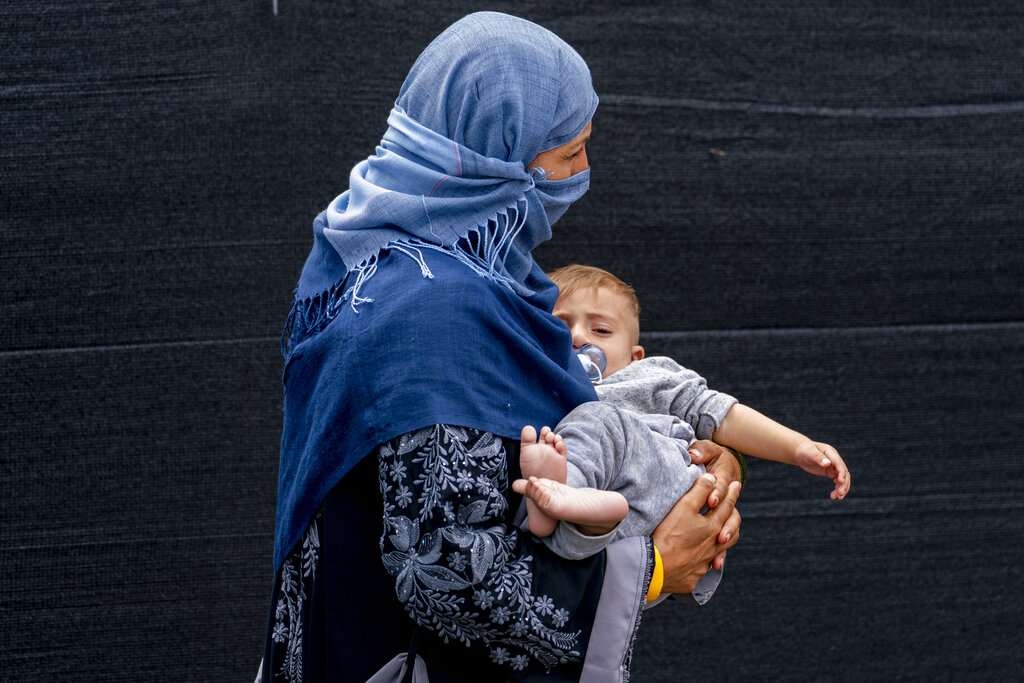 A woman evacuated from Afghanistan steps off a bus with a baby as they arrive at a processing center in Chantilly, Virginia