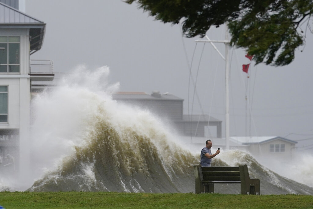 A man takes pictures of high waves along the shore of Lake Pontchartrain