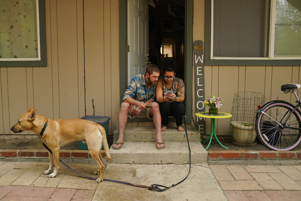 Sierra Fowzer, right, and Skylor Klitsch, a couple who chose not to evacuate, look at their phone for updates on the Caldor Fire in South Lake Tahoe, Calif.