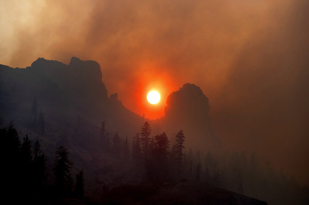 Smoke from the Caldor Fire wafts over a ridgetop near Kirkwood Ski Resort in Eldorado National Forest, Calif.