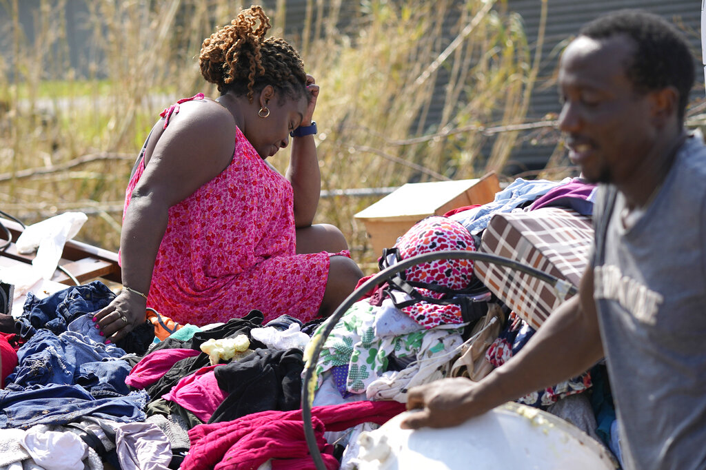 Woman pauses while salvaging belongings from her destroyed home after Hurricane Ida