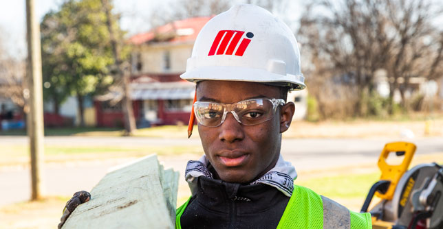 Build Up student wearing hard hat carrying wood