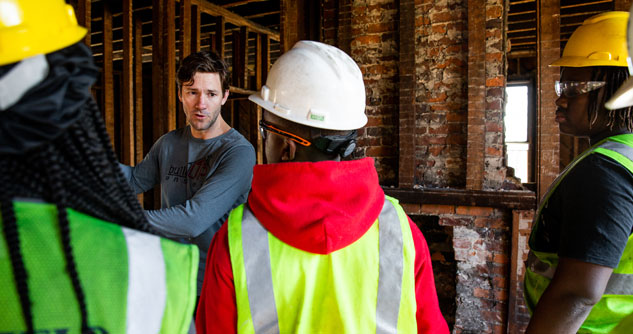 man explaining construction to kids in hard hats