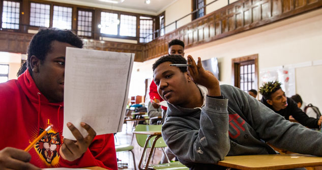 Two boys comparing notes in class