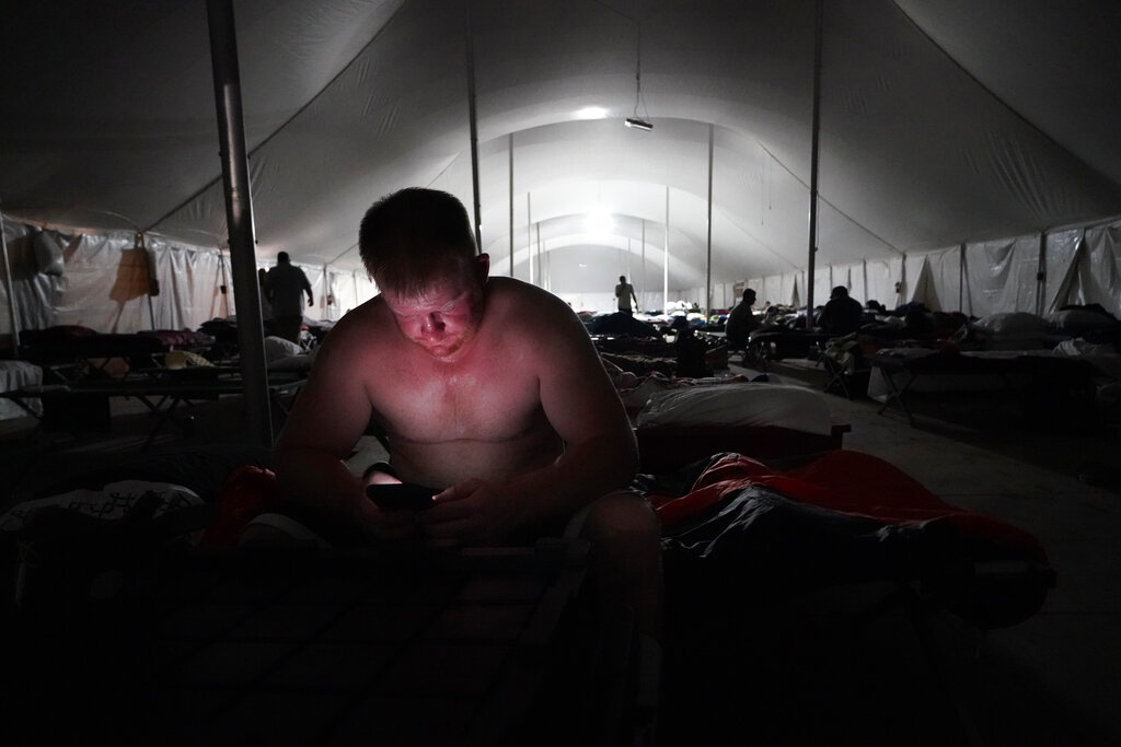 Bryan Willis, of Stilwell, Okla., an electrical worker for Ozarks Electric, looks at his phone before going to bed in a tent city for electrical workers in Amelia, La.