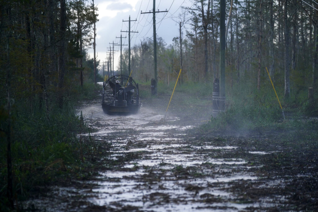 Electrical workers ride through marsh in an airboat to restore power lines in the aftermath of Hurricane Ida