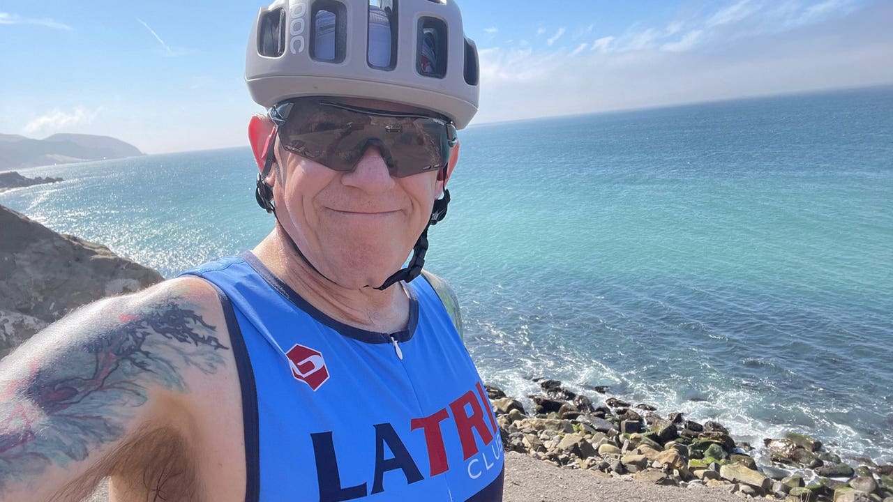 Smiling man wearing a helmet and tank top near ocean